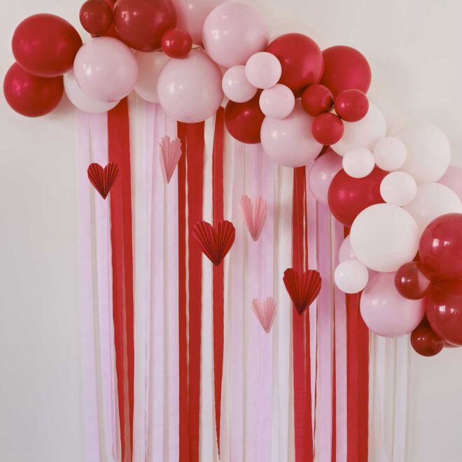 Piros és rózsaszín lufigirland háttér szalagokkal és papír szívdíszekkel
